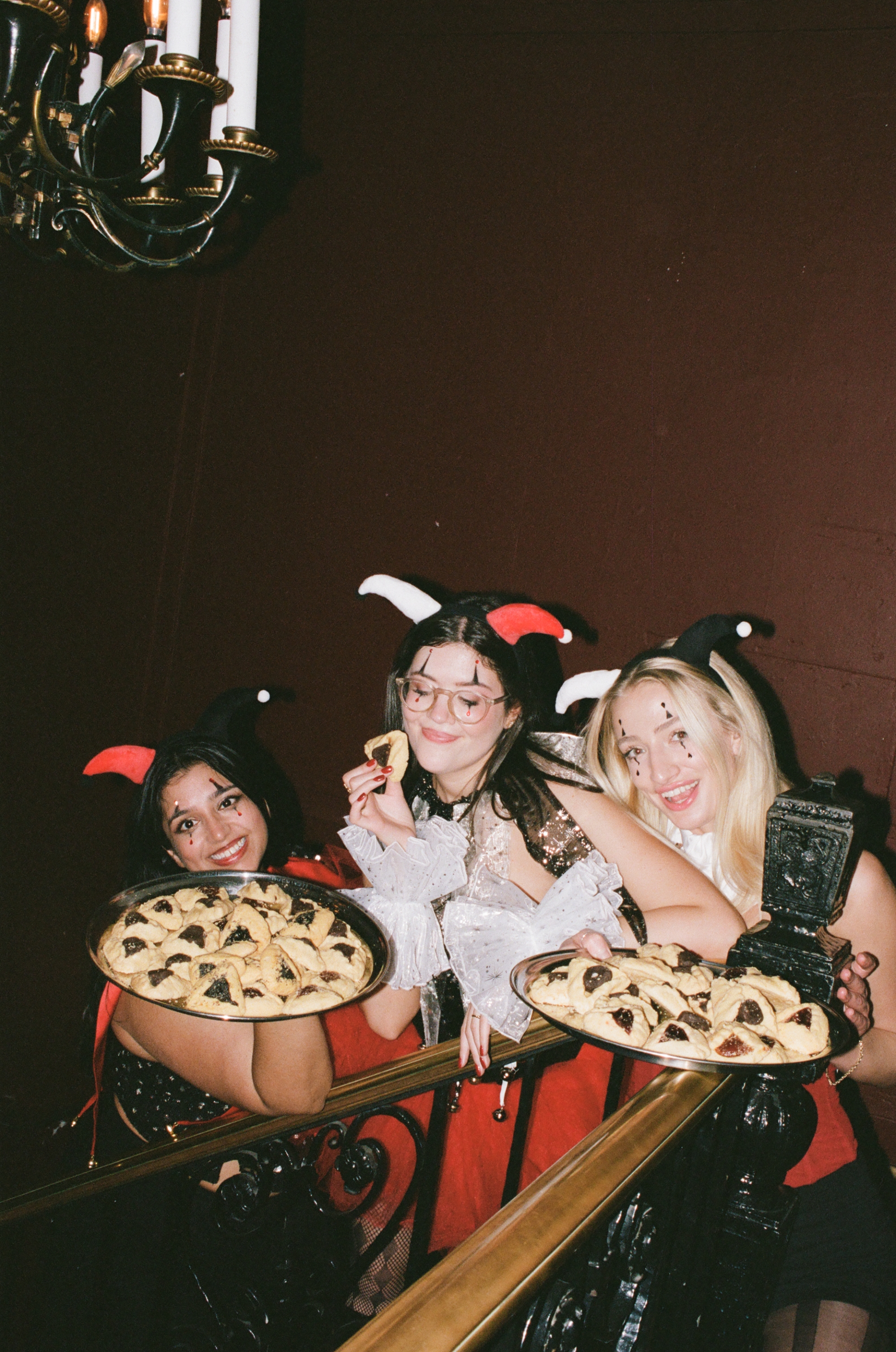 Guests in Purim costumes holding trays of hamantaschen on a staircase