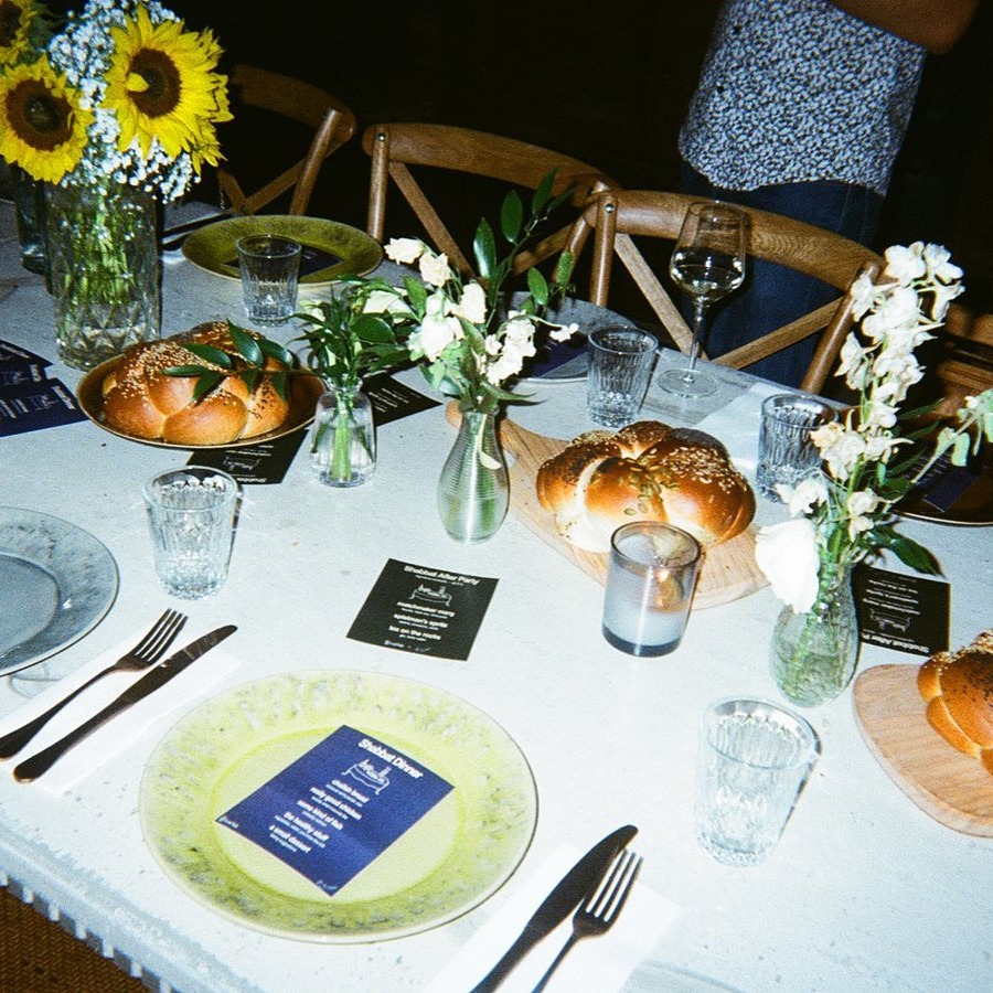 Candlelit Shabbat dinner party with friends around a long table in New York City