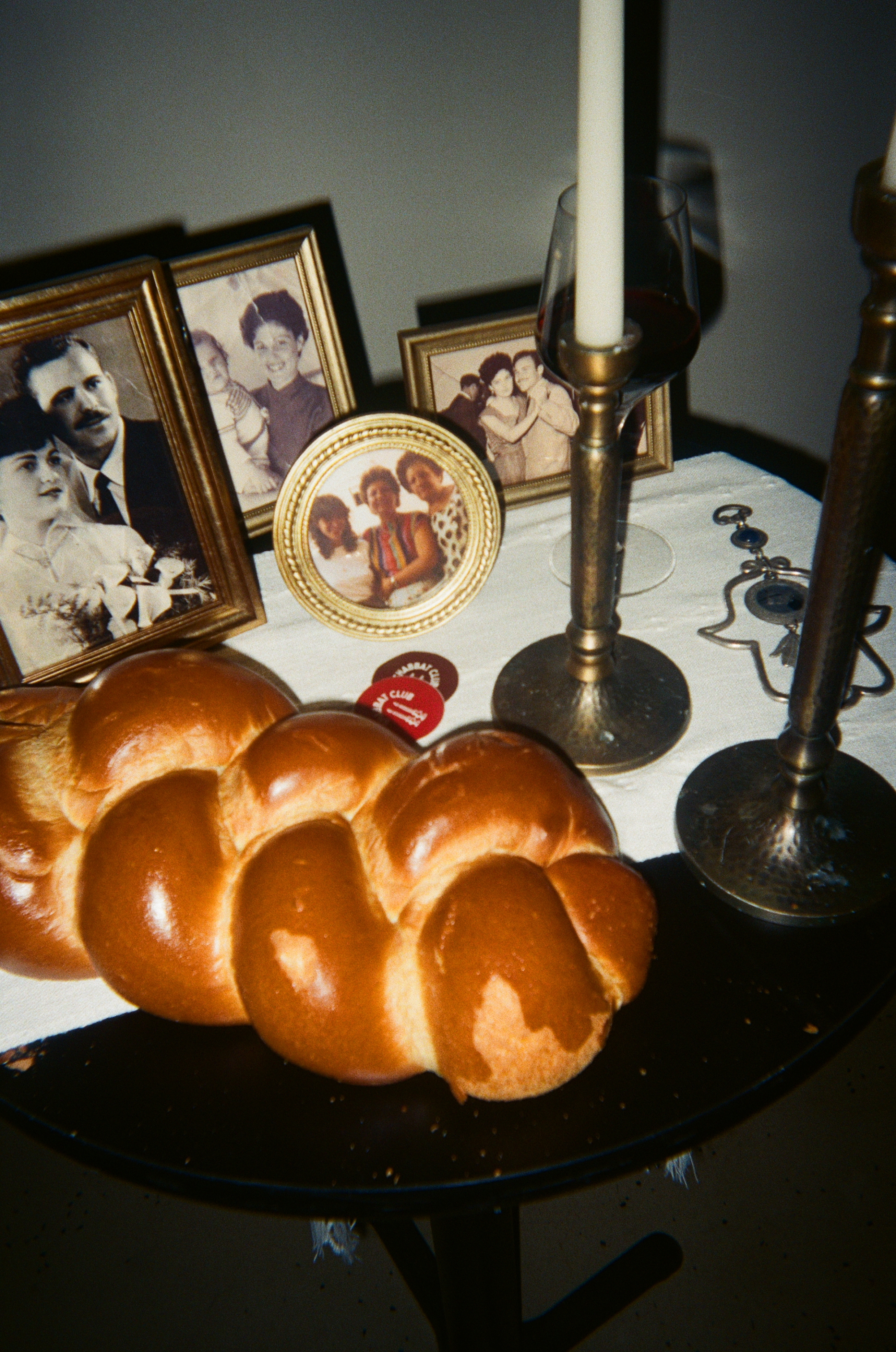 A candlelit Shabbat Club dinner table set with challah and flowers