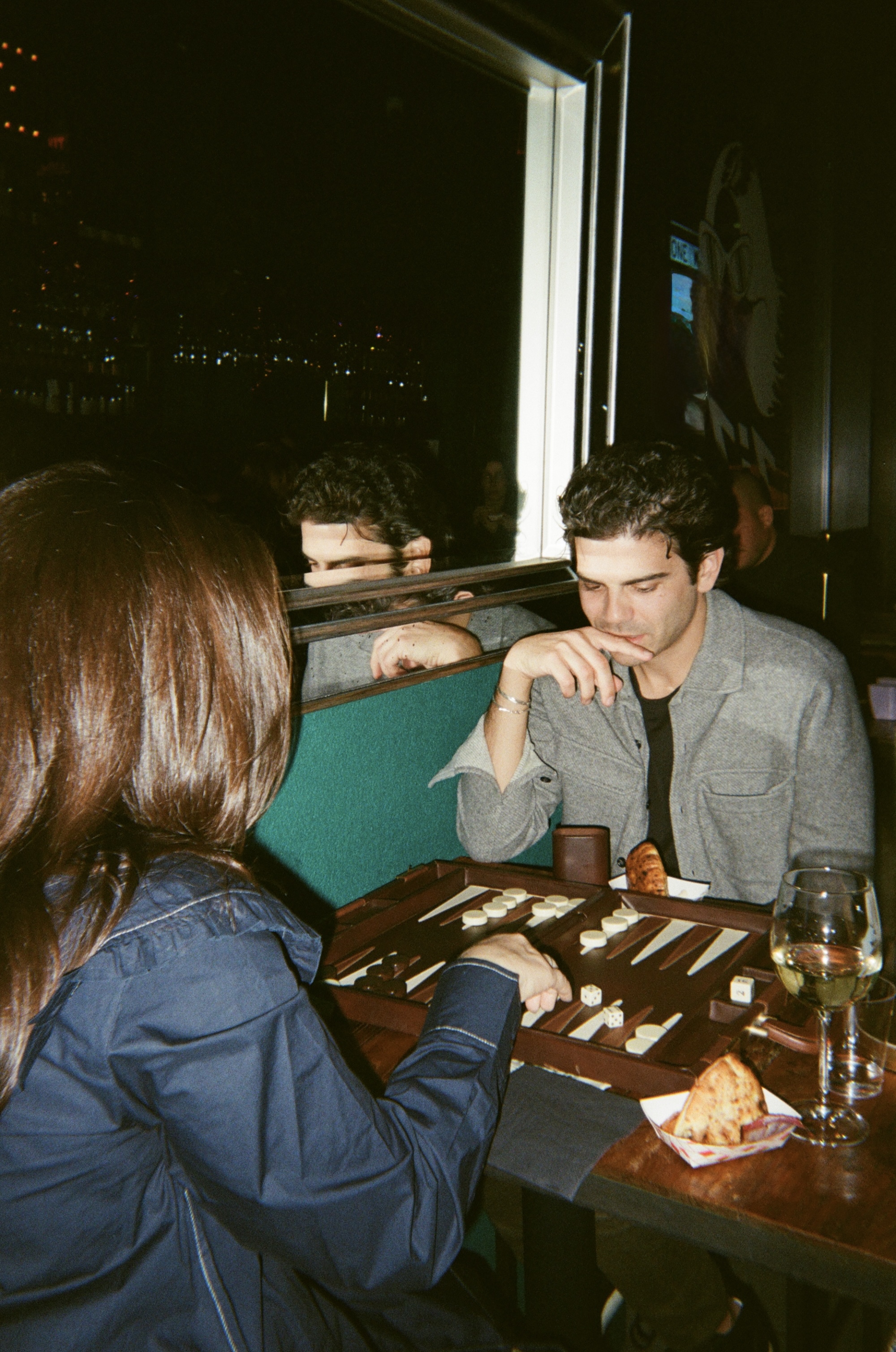 Guests playing backgammon with wine and snacks at an Almost Shabbat mixer
