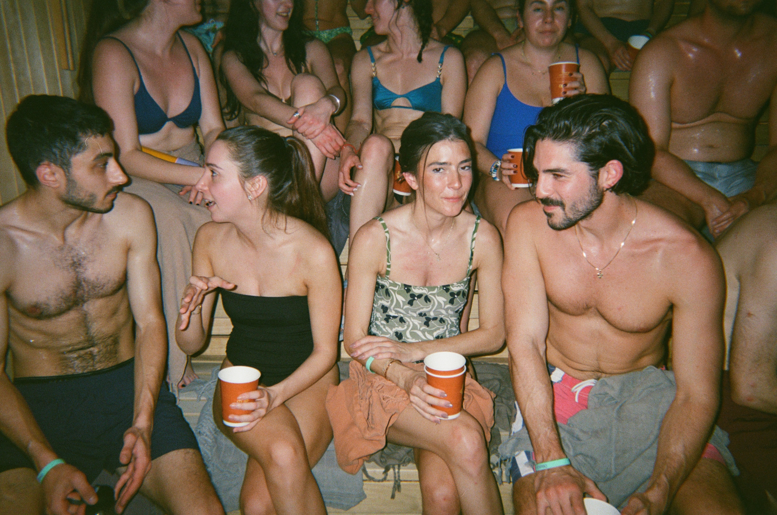 Guests sitting together in the sauna with drinks at a Shvitz Club gathering