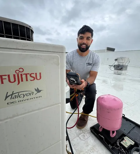 HVAC technician working on copper refrigerant lines of an air conditioner