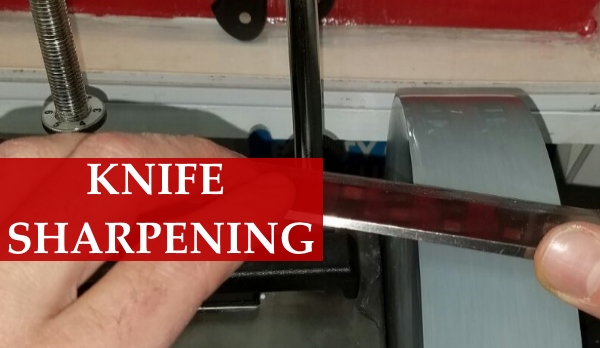 Chef knife blade being sharpened on a professional sharpening wheel