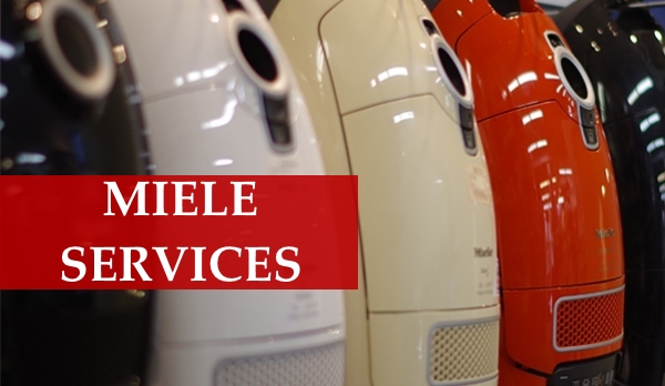 Technician repairing a Miele vacuum cleaner on a workbench