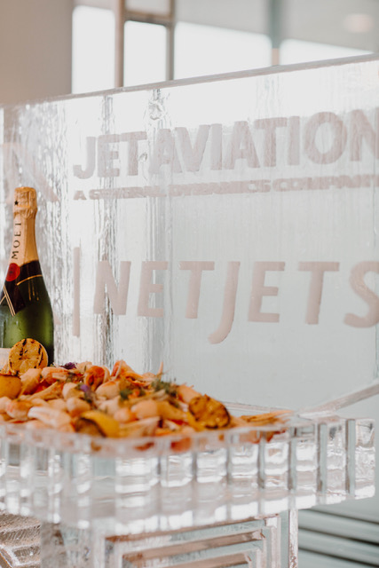 A catered seafood display with champagne in front of a carved ice sculpture