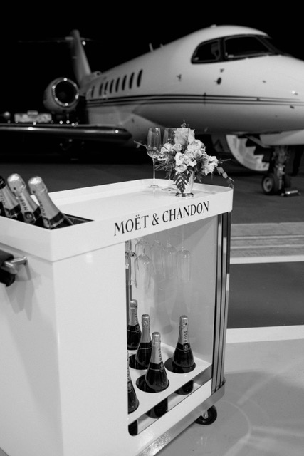 A Moët & Chandon champagne cart with flutes and flowers beside a private jet on the Scottsdale Airport runway
