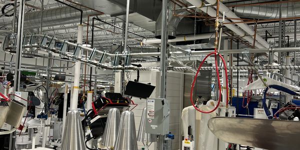 Industrial laundry facility with equipment, ducts, and a green ladder.