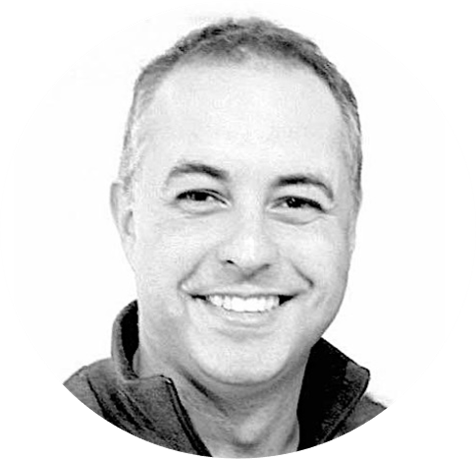 Black and white photo of a smiling man in a collared shirt.