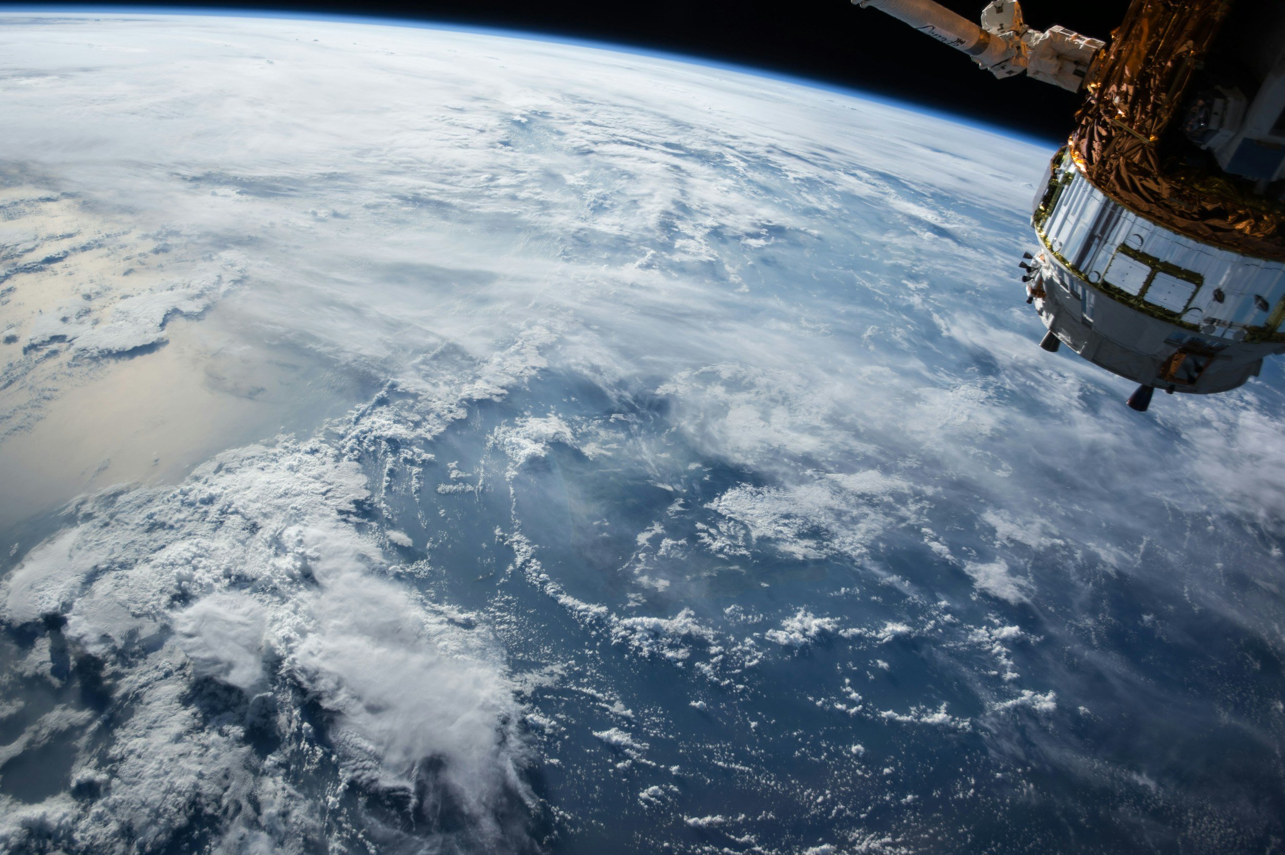 View of Earth from space with a spacecraft visible in the upper right corner.